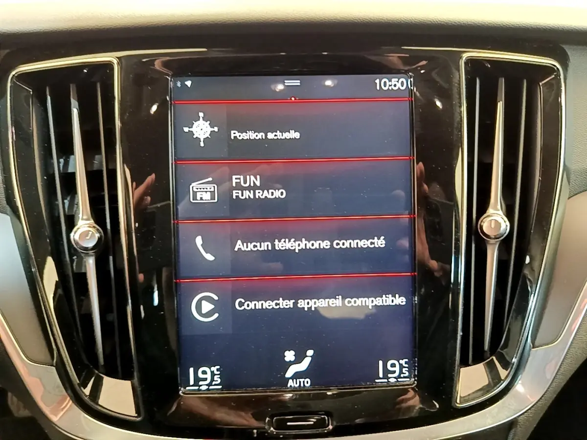 Écran tactile central du tableau de bord noir d'une Volvo V60 D3 Business, affichant la navigation et la radio.