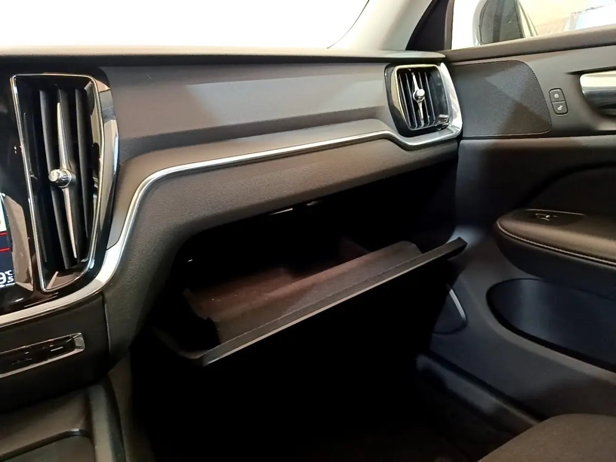 Intérieur noir de la Volvo V60 2020, vue côté passager avec boîte à gants ouverte et aérateurs rectangulaires.