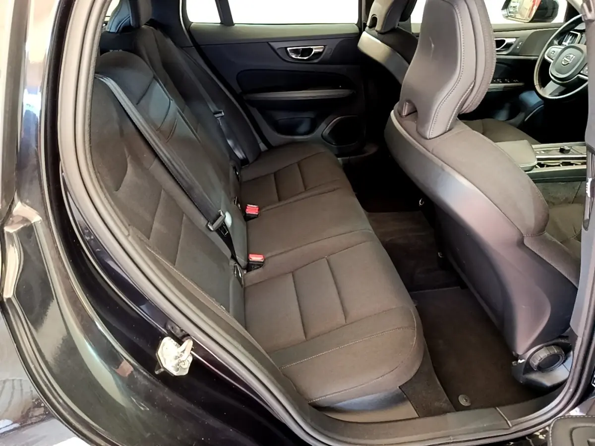 Vue intérieure côté gauche montrant la banquette arrière noire et l'avant avec le volant d'une Volvo V60 D3 Business 2020.
