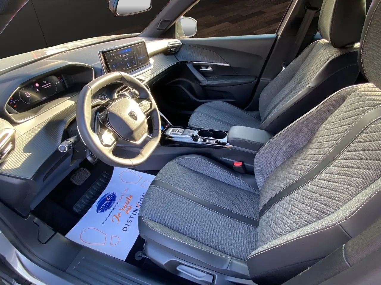 Vue intérieure côté conducteur du Peugeot 2008 2024 avec sièges tissu gris et tableau de bord moderne.