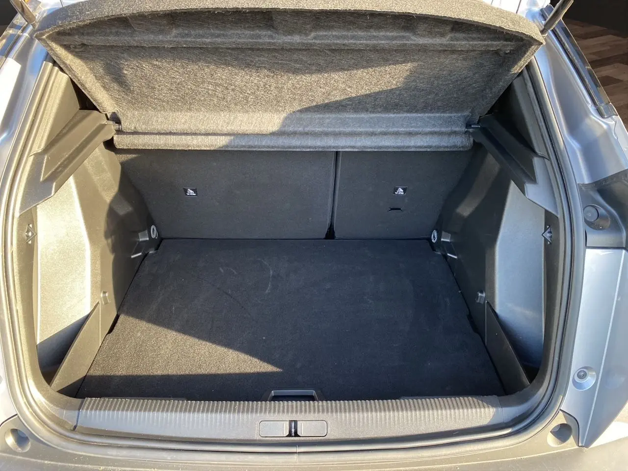 Coffre ouvert en vue arrière d'un Peugeot 2008 gris Artense, montrant un espace de chargement propre et spacieux.