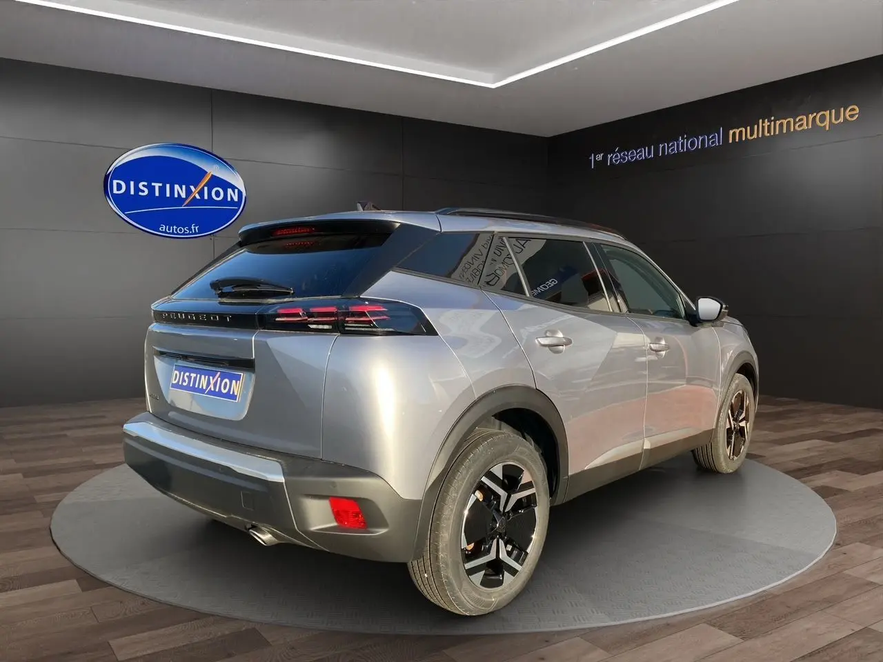 Vue 3/4 arrière droit d'un Peugeot 2008 gris Artense avec jantes noires et toit noir dans un showroom.