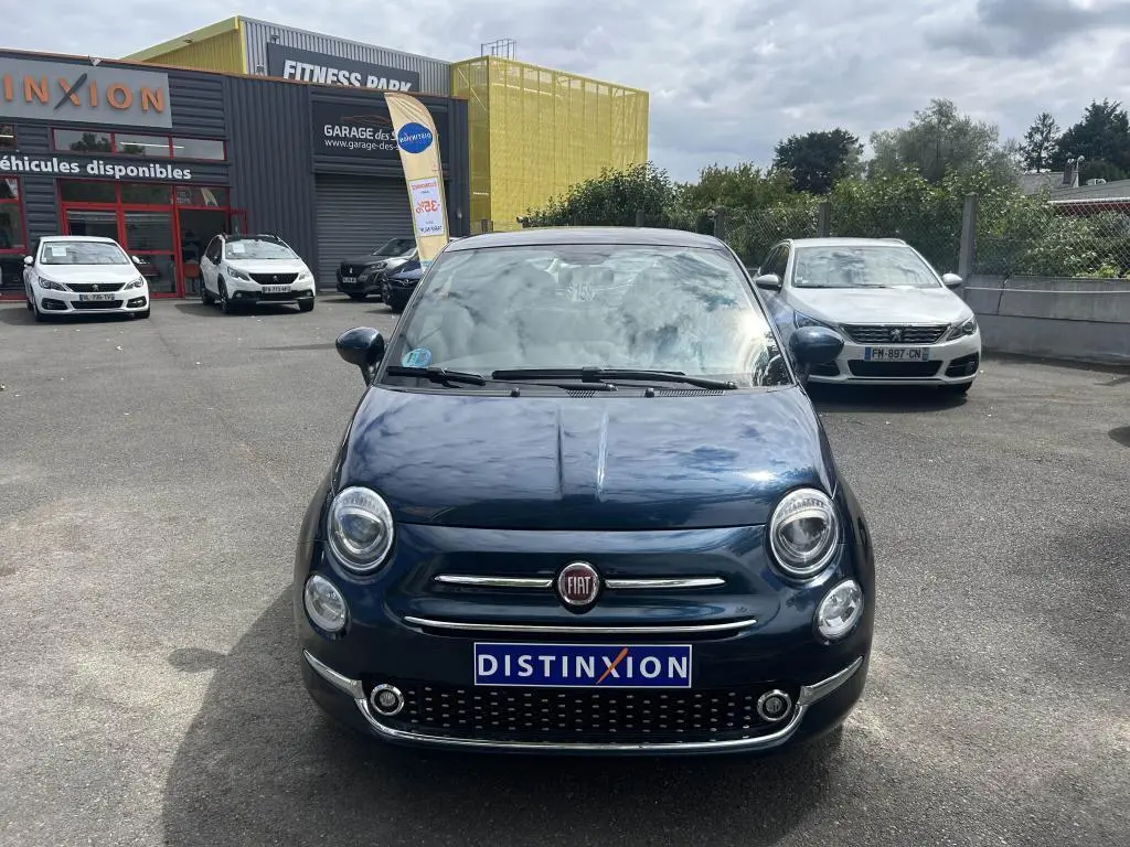 Vue de face d'une Fiat 500 2024 bleu avec toit vitré panoramique et jantes alliage 16'' Spider sur parking.