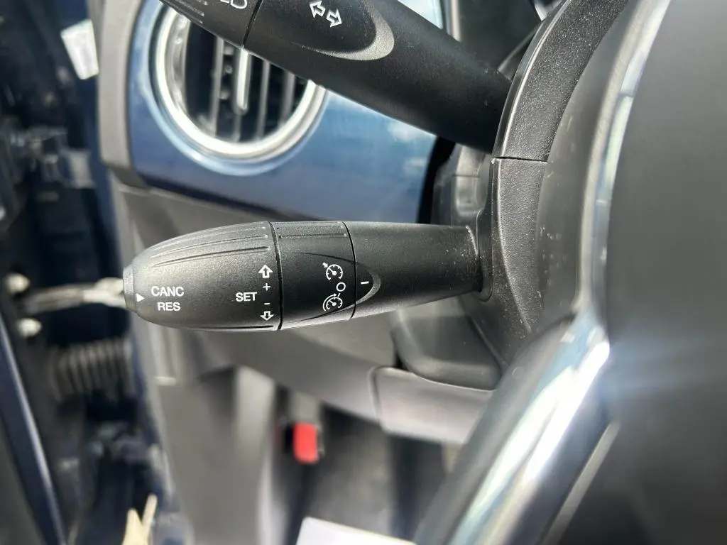 Gros plan sur la commande de régulateur de vitesse noire dans l'habitacle bleu d'une Fiat 500 2024 Dolcevita.