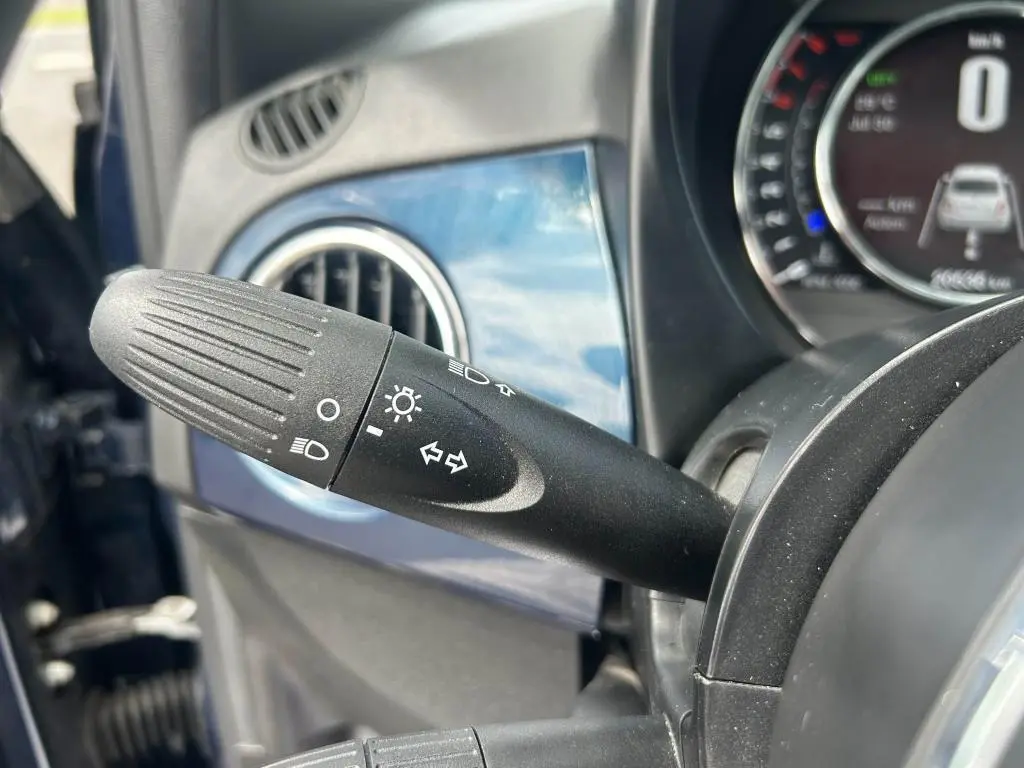 Gros plan sur la manette des clignotants et phares dans l'habitacle bleu d'une FIAT 500 2024 côté gauche.