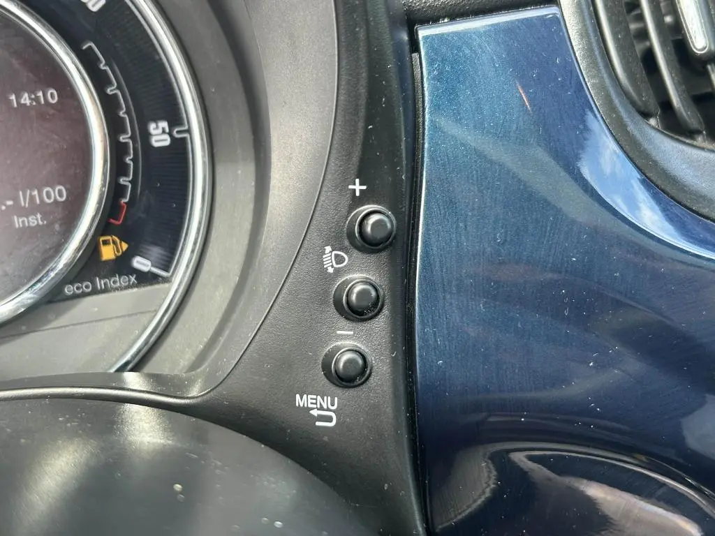 Détail des commandes d'éclairage et menu sur tableau de bord bleu du Fiat 500 2024 côté gauche.