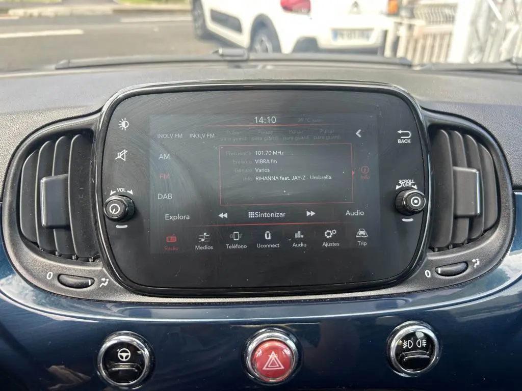 Vue rapprochée de l'écran tactile central du tableau de bord bleu d'une Fiat 500 2024 avec commandes audio et ventilation.