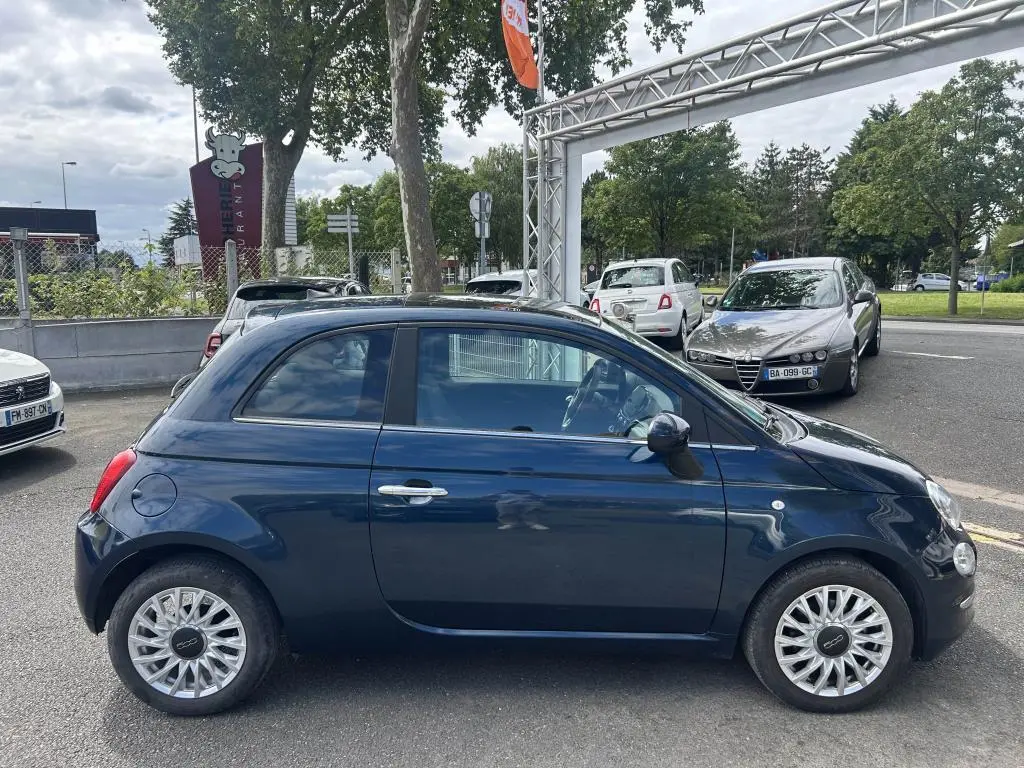 Profil côté gauche d'une FIAT 500 2024 bleu avec jantes alliage 16'' Spider, stationnée en extérieur.