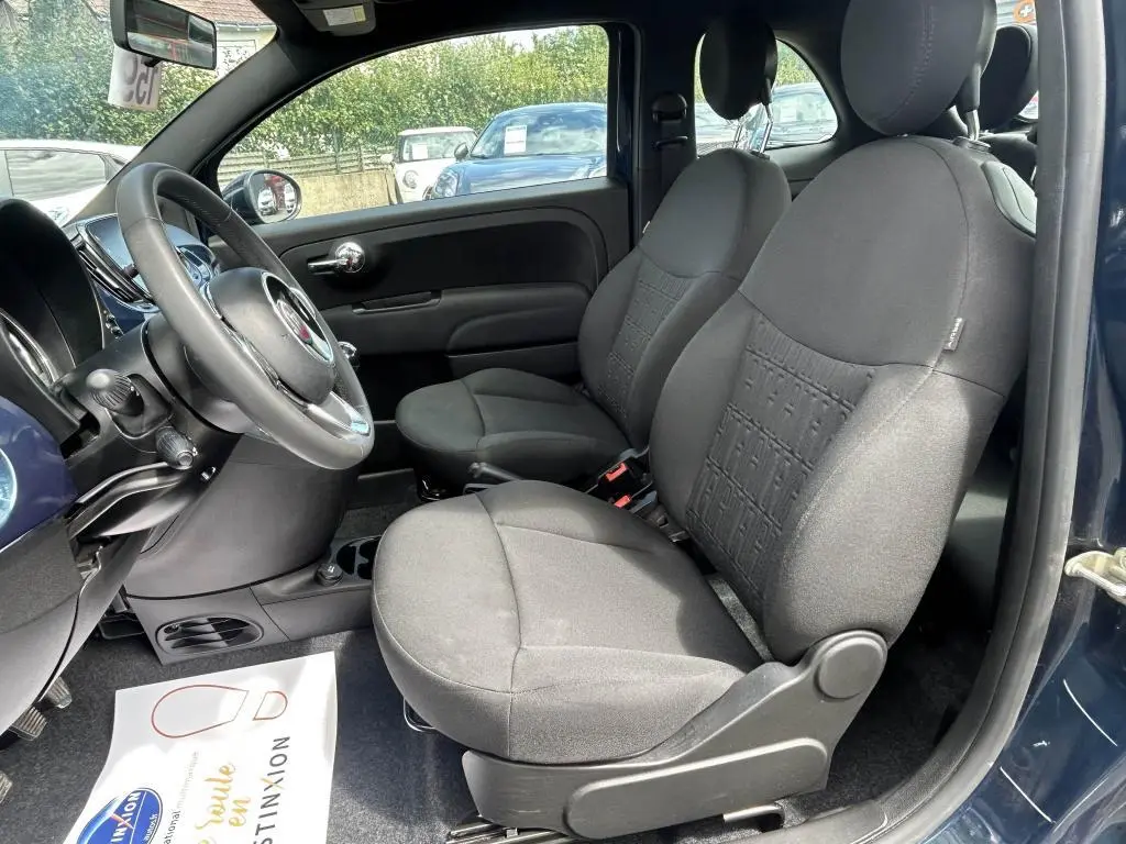 Intérieur de la FIAT 500 2024 bleu, vue côté gauche montrant les sièges avant en tissu noir et le volant multifonction.