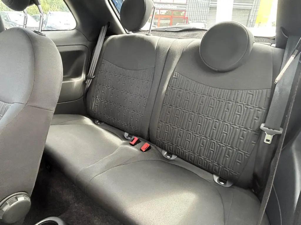 Vue intérieure arrière du siège noir de la Fiat 500 2024 avec motifs FIAT embossés et ceintures de sécurité visibles.