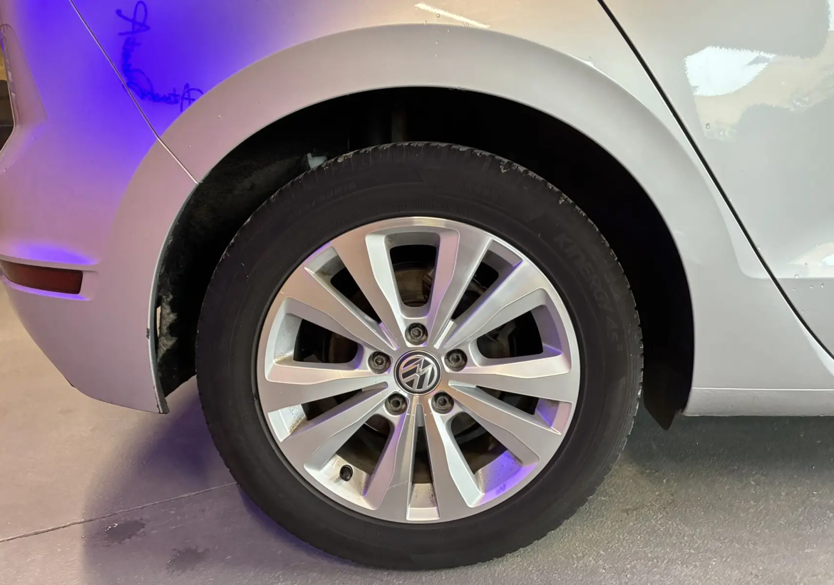 Gros plan sur la roue arrière droite grise d'une Volkswagen Golf Sportsvan 2019 avec jante alliage et logo VW visible.