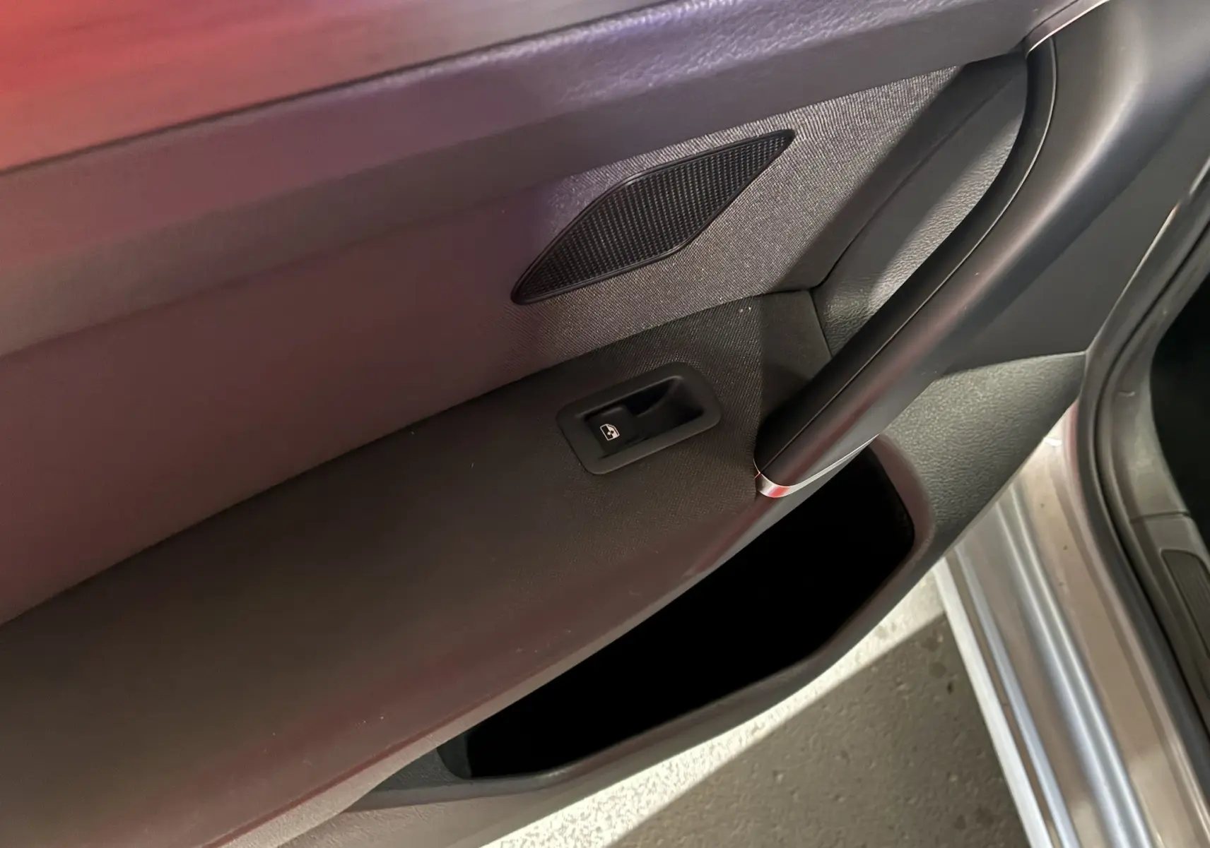 Gros plan sur la porte intérieure côté gauche d'une Volkswagen Golf Sportsvan gris, avec commande de lève-vitre et haut-parleur intégré.