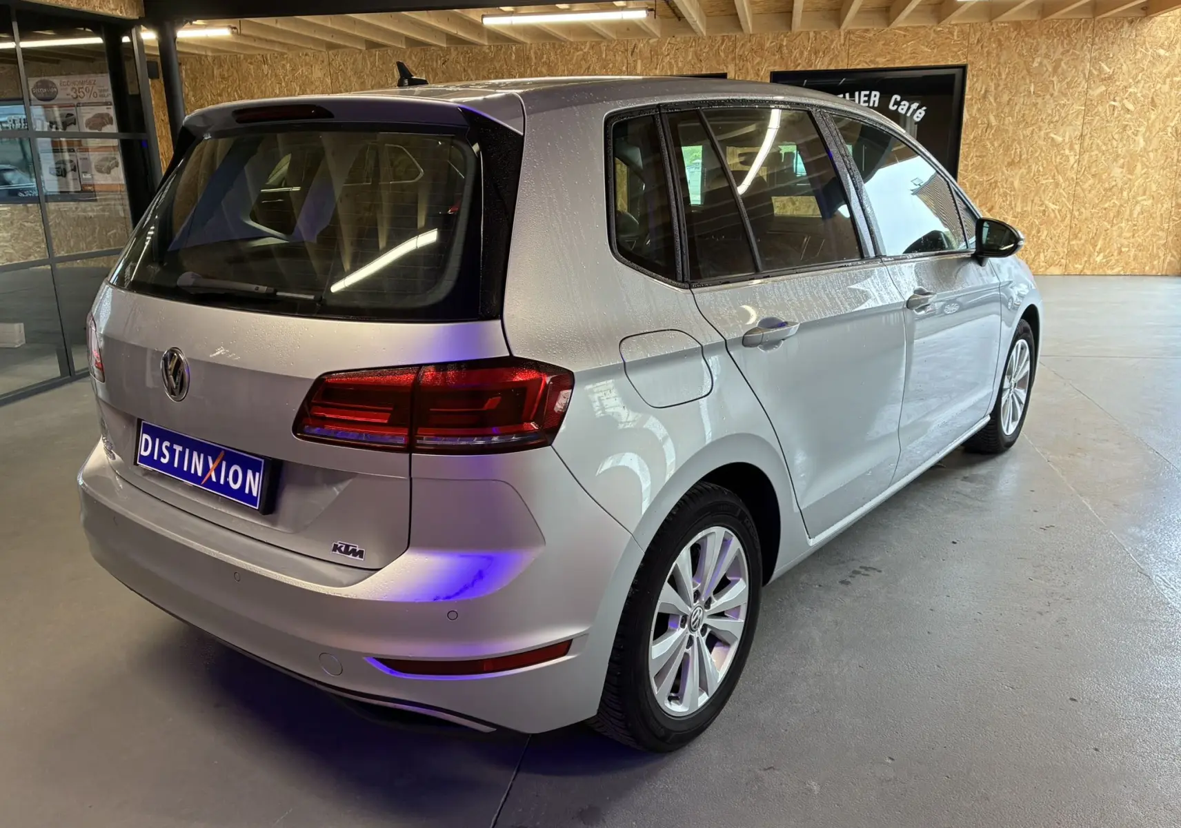 Vue 3/4 arrière droite d'une Volkswagen Golf Sportsvan gris métallisé, avec feux arrière LED et cinq portes visibles.