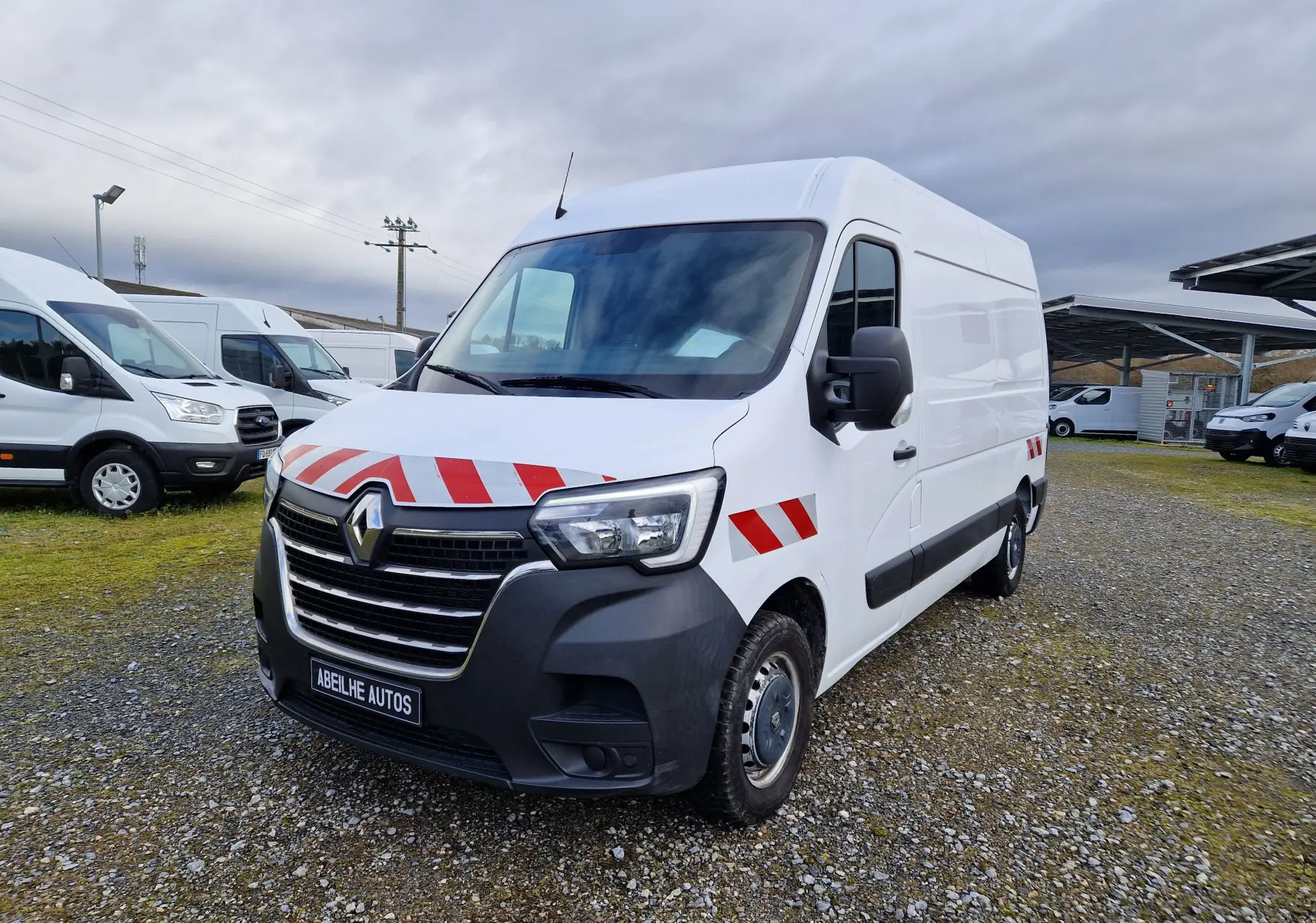 Vue 3/4 avant droite d’un Renault Master blanc 2020 avec bandes rouges réfléchissantes sur capot et ailes.