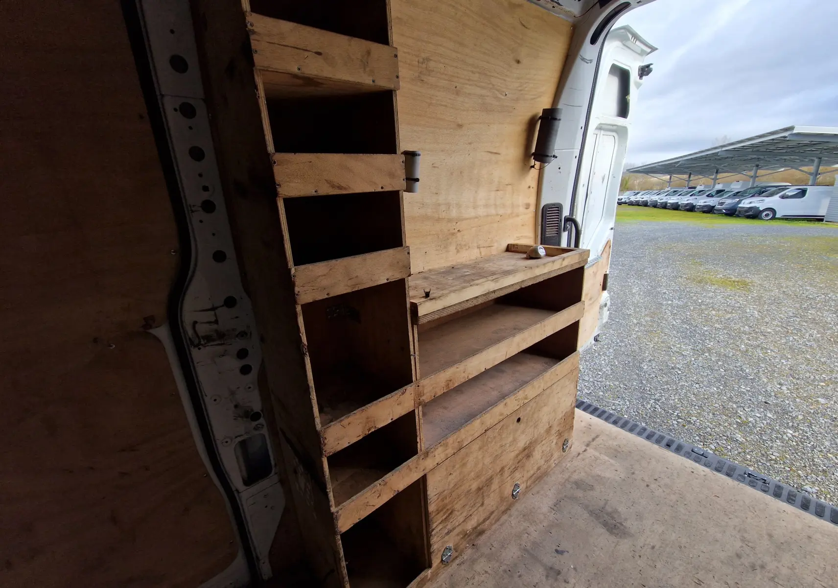 Vue intérieure arrière droite du Renault Master blanc 2020 avec aménagements en bois pour rangement.