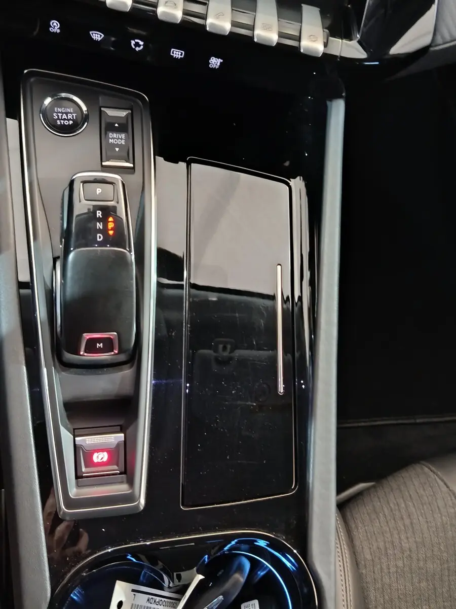 Vue rapprochée de la console centrale noire brillante du Peugeot 508 BlueHDi 130, avec levier de vitesses automatique et bouton start/stop.