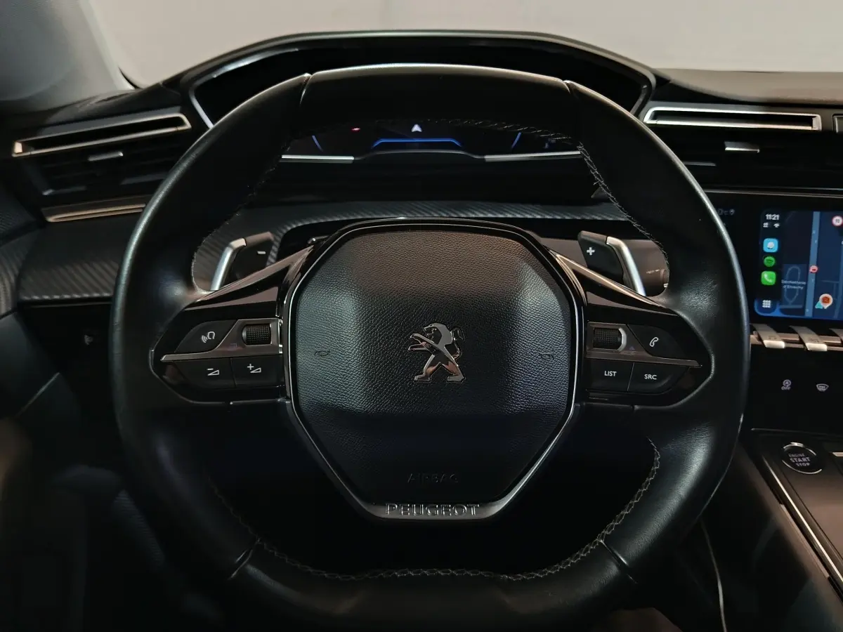 Vue rapprochée du volant cuir noir de la Peugeot 508 2020 avec commandes intégrées et tableau de bord digital.