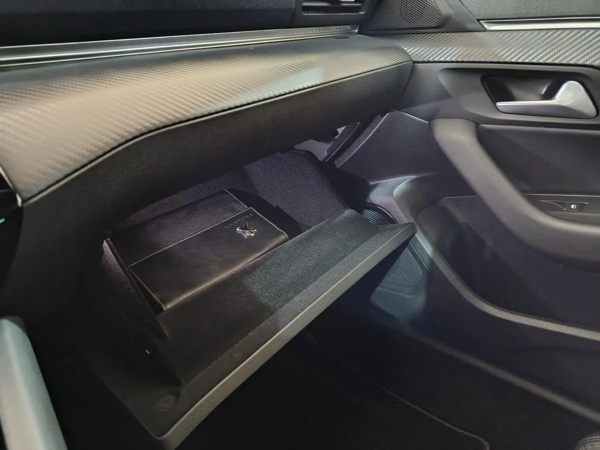 Vue intérieure côté passager du coffre à gants ouvert d’une Peugeot 508 gris clair avec manuel de bord visible.
