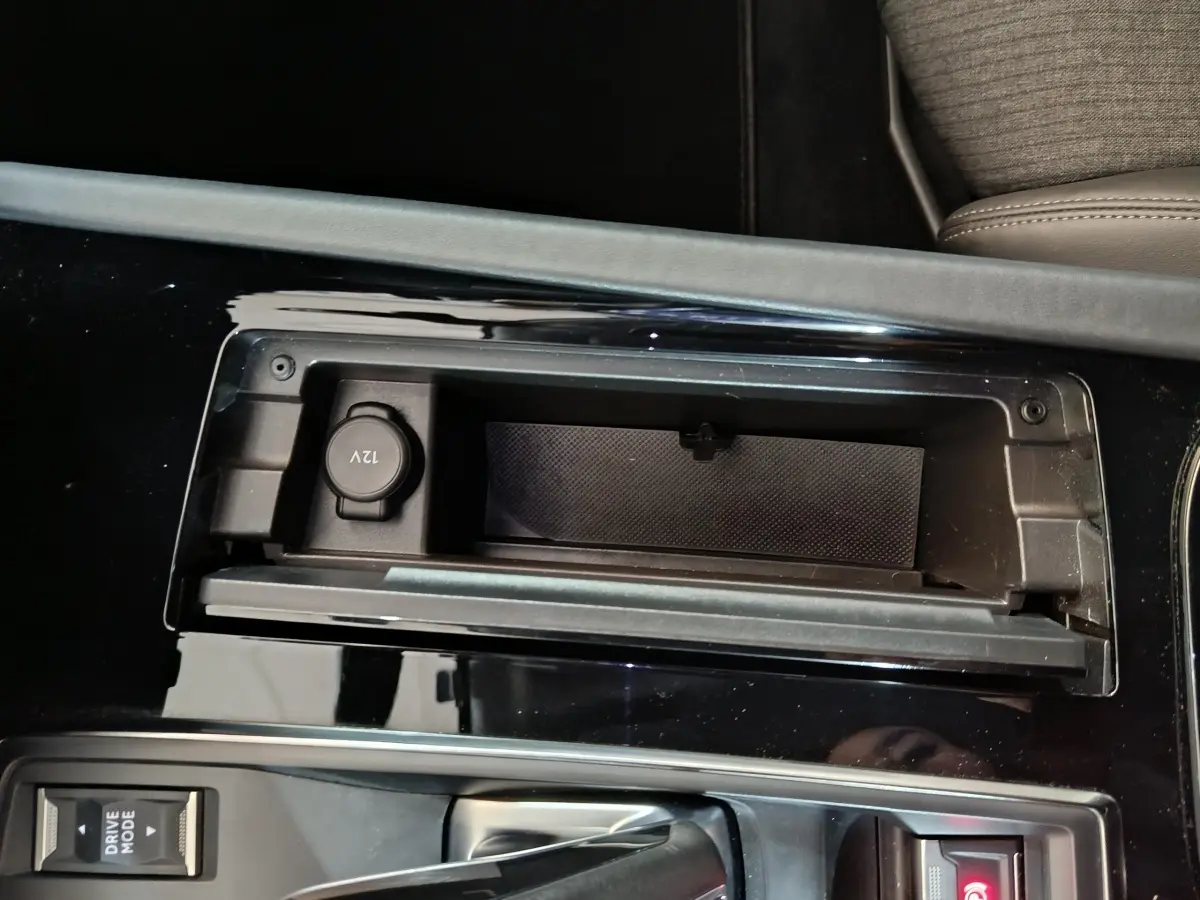 Gros plan sur la console centrale noire du Peugeot 508 gris clair, avec prise 12V et levier de boîte automatique.
