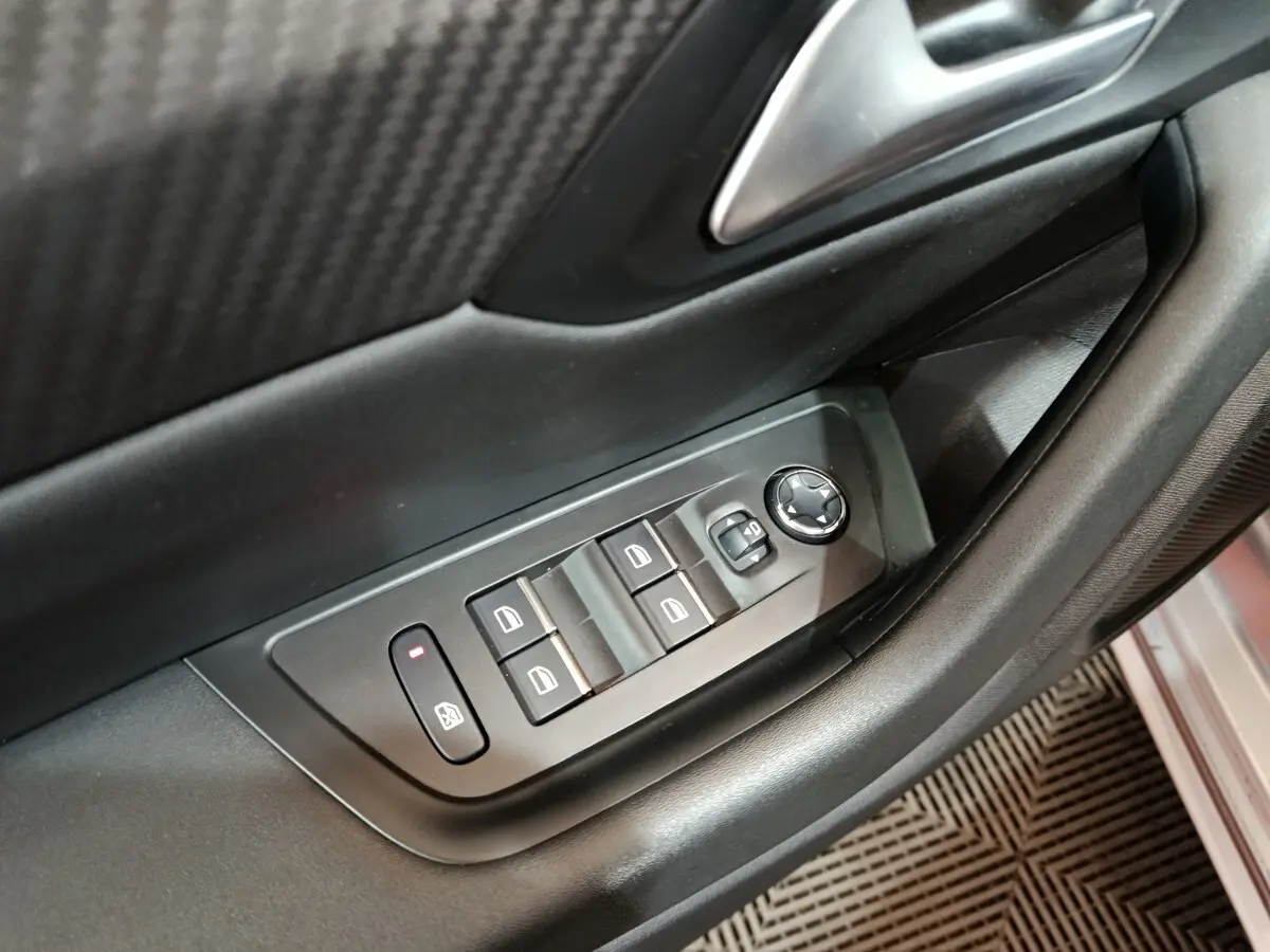 Détail des commandes des vitres et rétroviseurs sur la porte côté conducteur d'une Peugeot 508 gris clair 2020.