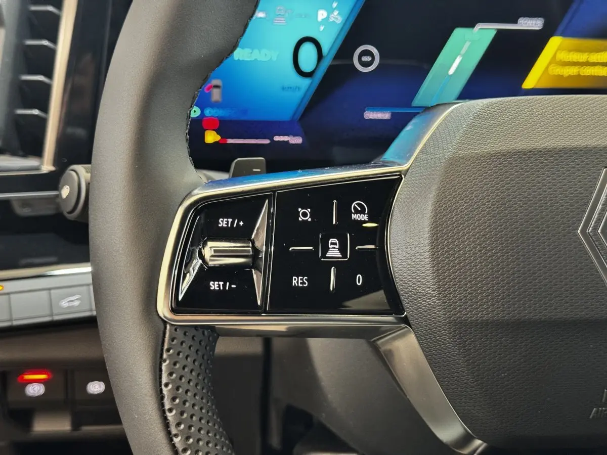 Gros plan sur la partie gauche du volant noir du Renault Espace 2025 avec commandes de régulateur et écran numérique en arrière-plan.