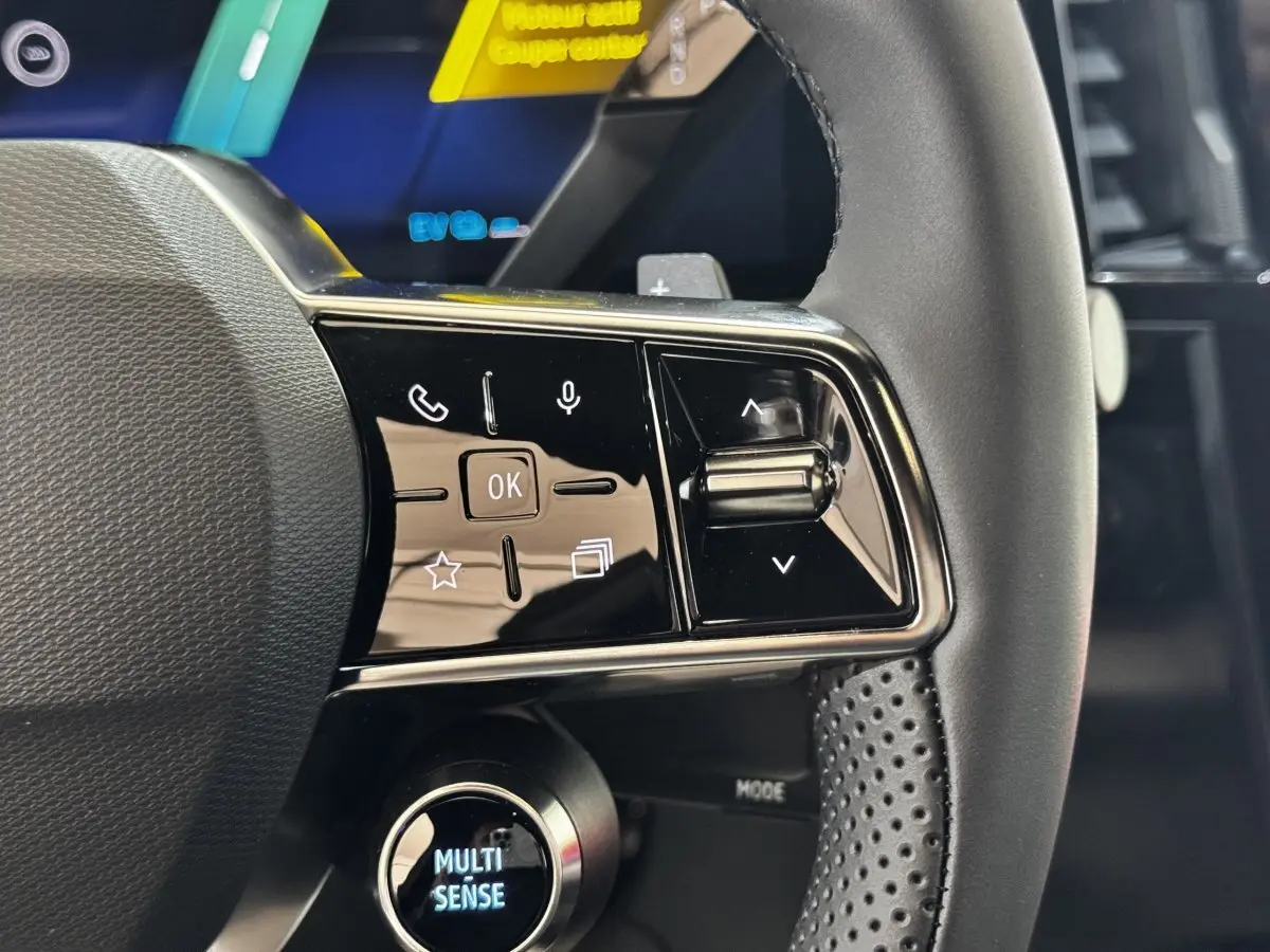 Gros plan sur les commandes gauche du volant cuir perforé du Renault Espace noir 2025 version techno hybride.