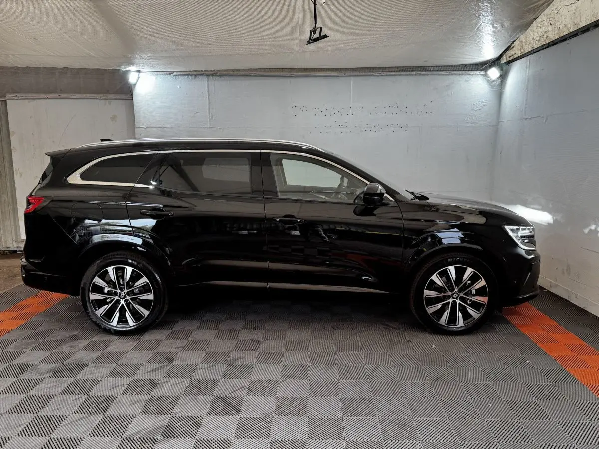 Profil droit du Renault Espace noir 2025 avec jantes alliage et rails de toit chromés en intérieur fermé.