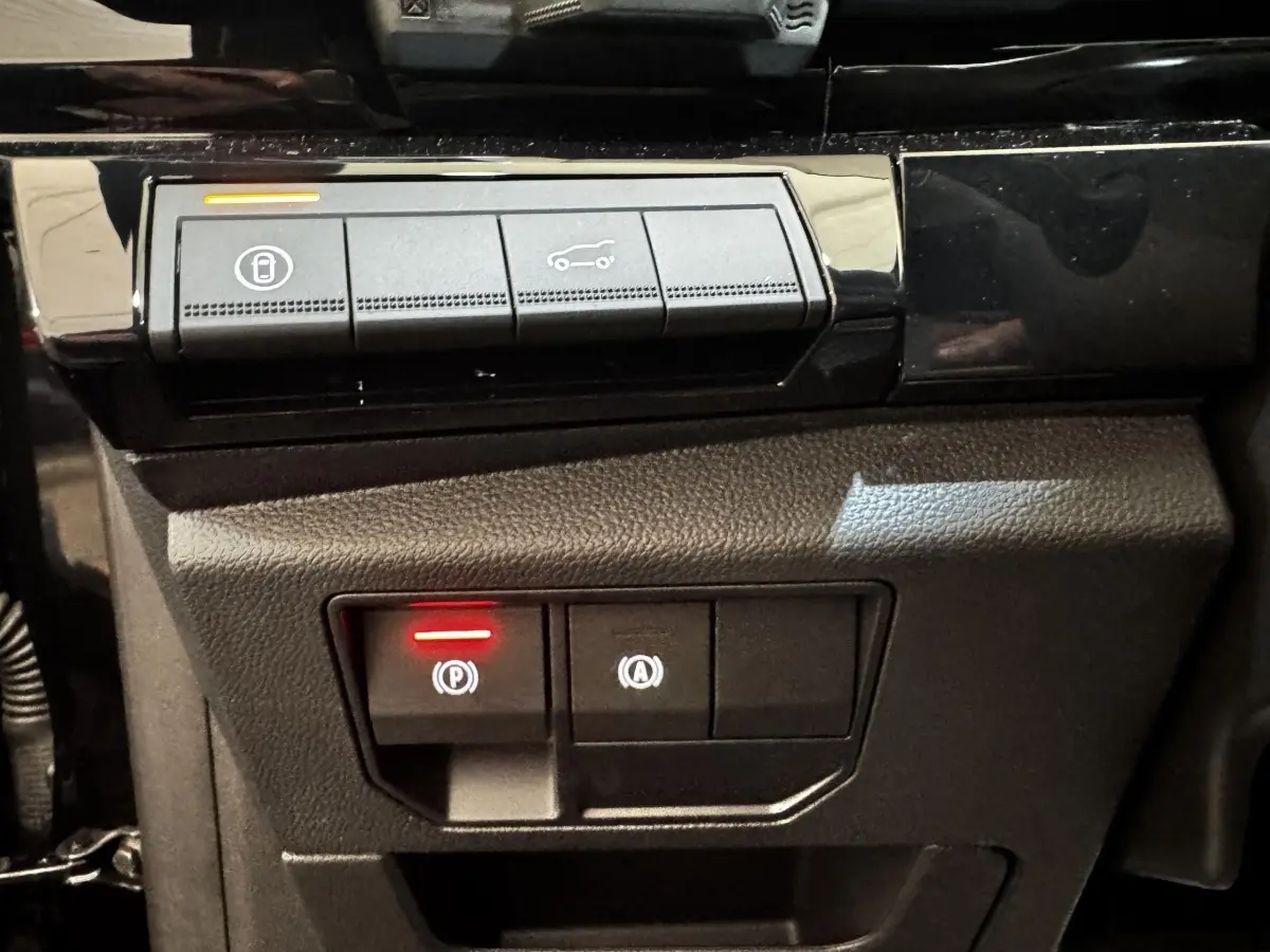 Gros plan sur les commandes du frein à main électrique et ouverture du coffre du Renault Espace noir 2025.