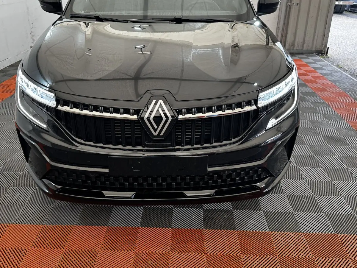 Vue frontale rapprochée du Renault Espace noir 2025 avec calandre chromée et phares LED allumés.