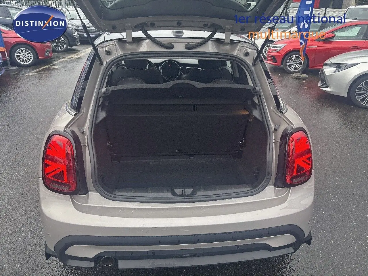 Vue arrière ouverte d'une MINI 1.5 136CH STEPTRONIC Rooftop Grey Metal, coffre vide et feux arrière Union Jack rouges visibles.