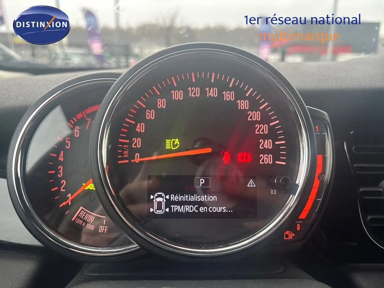 Tableau de bord de MINI 2023 avec compteur central et affichage digital, éclairage rouge et gris rooftop visible.