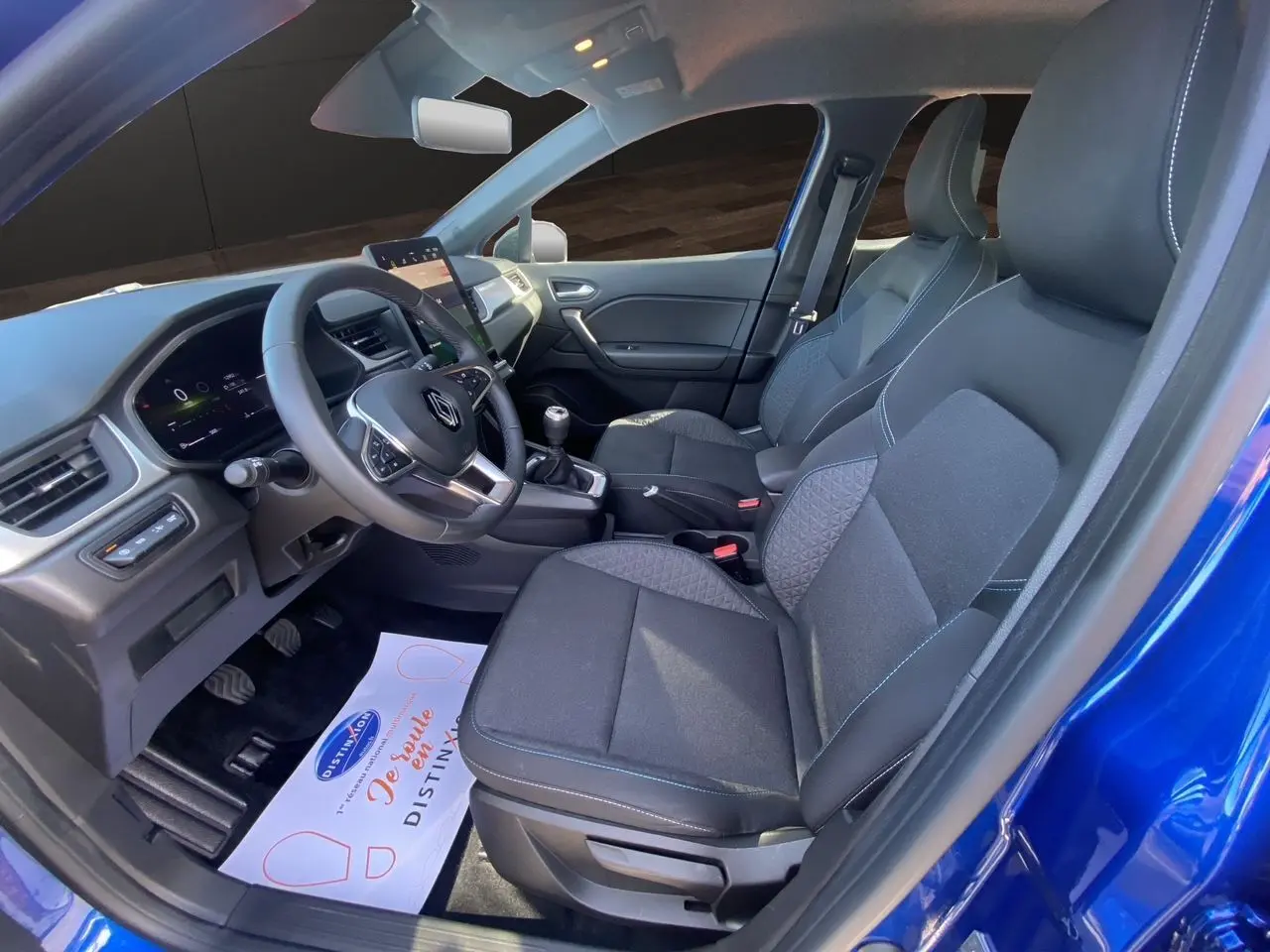 Vue intérieure côté conducteur du Renault Captur TCE 90 Evolution 2024 en bleu Iron avec toit noir, volant et tableau de bord visibles.