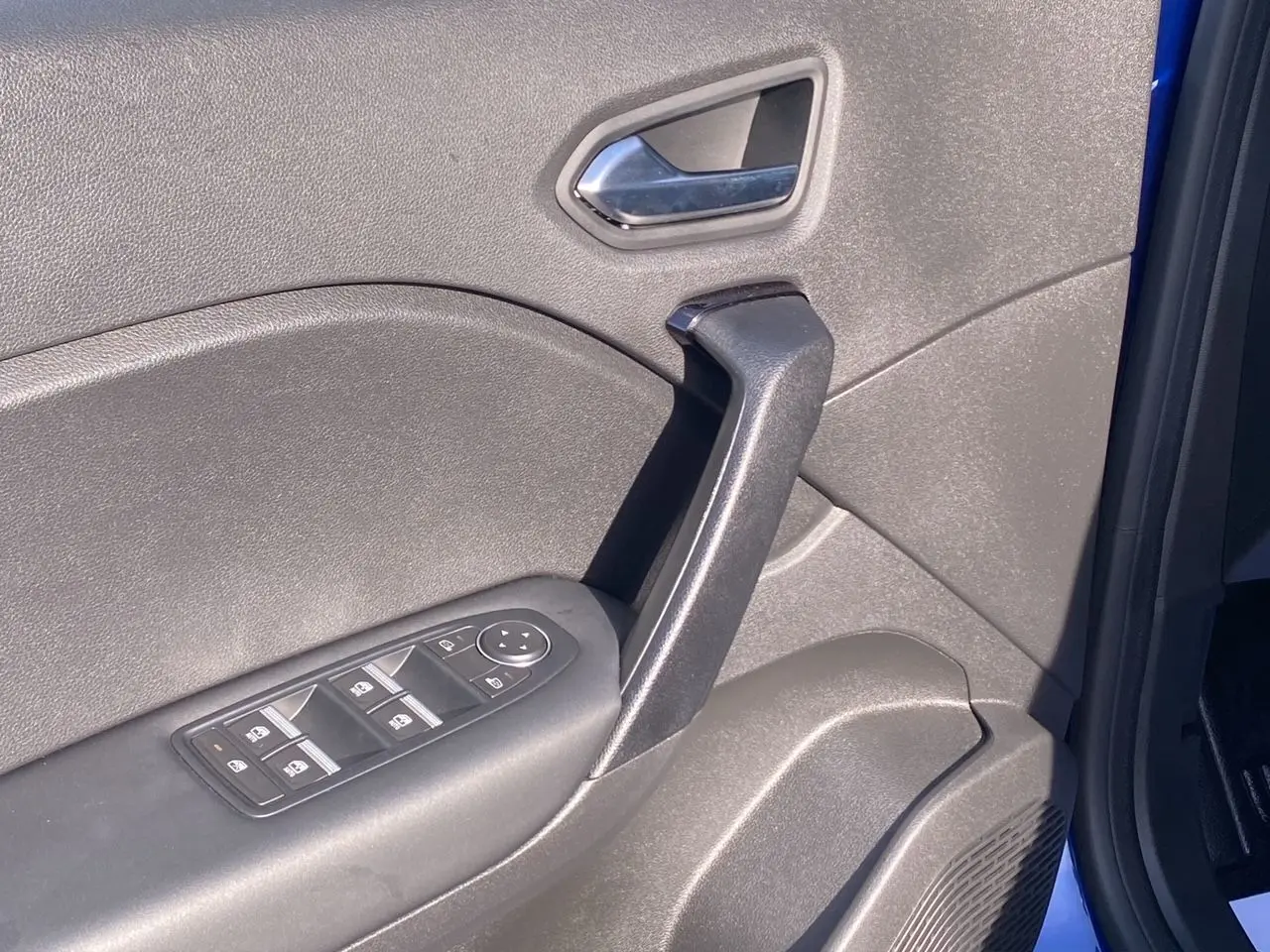 Détail de la porte avant gauche du Renault Captur 2024 bleu Iron, montrant la poignée et les commandes des vitres.