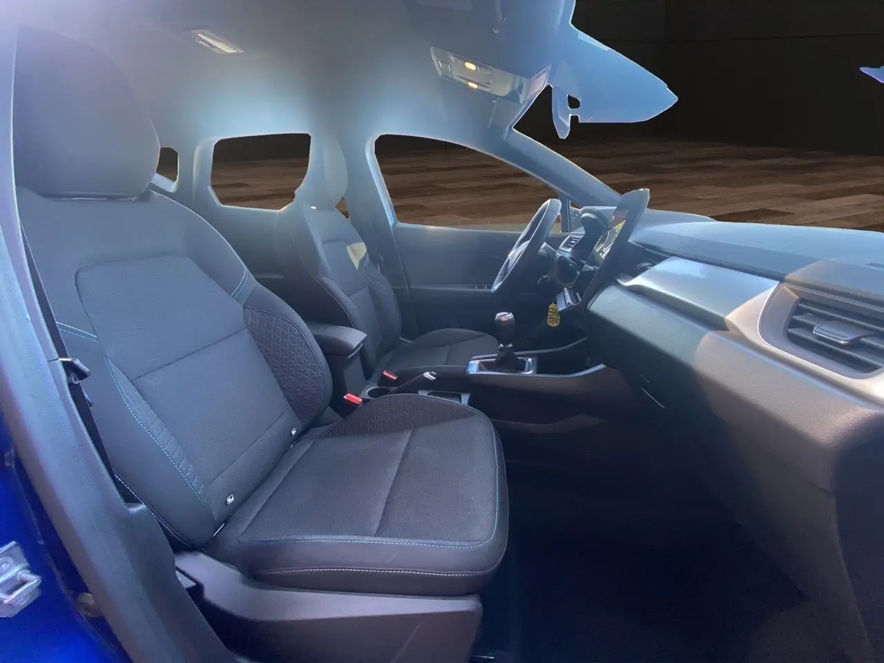 Intérieur avant du Renault Captur TCE 90 Evolution 2024, sièges noirs et tableau de bord avec boîte manuelle.