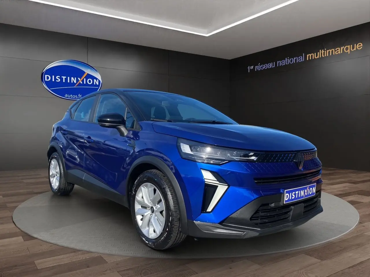 Renault Captur TCE 90 Evolution 2024 bleu Iron avec toit noir, vue 3/4 avant mettant en valeur la calandre et phares LED.