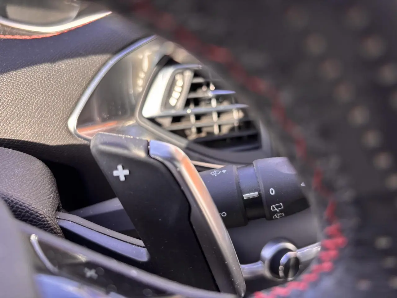 Gros plan sur la palette de changement de vitesse droite et la sortie d'air du tableau de bord d'une Peugeot 308 GT Line rouge foncé.