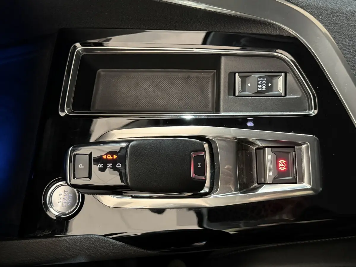 Vue rapprochée de la console centrale noire brillante du Peugeot 5008 avec levier de vitesse automatique et bouton start/stop.