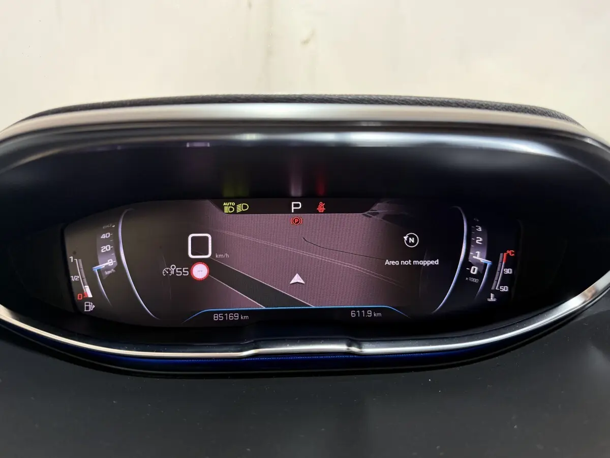 Vue rapprochée du tableau de bord numérique du Peugeot 5008 gris clair, affichant la navigation et les indicateurs de vitesse et température.