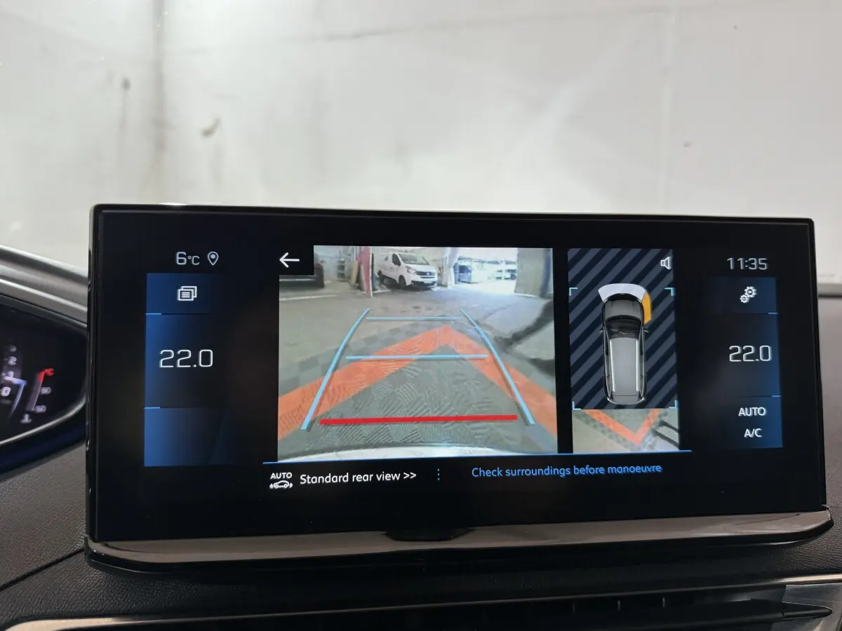 Écran tactile intérieur montrant la caméra de recul et l’aide au stationnement du Peugeot 5008 gris clair, version 2021.