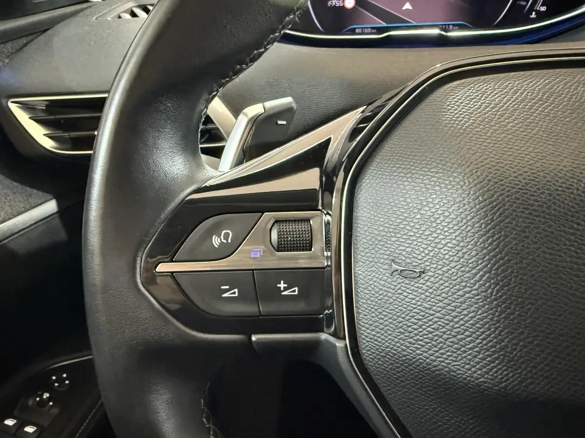 Gros plan sur le volant cuir noir du Peugeot 5008 2021, avec commandes multifonctions et palettes au volant.