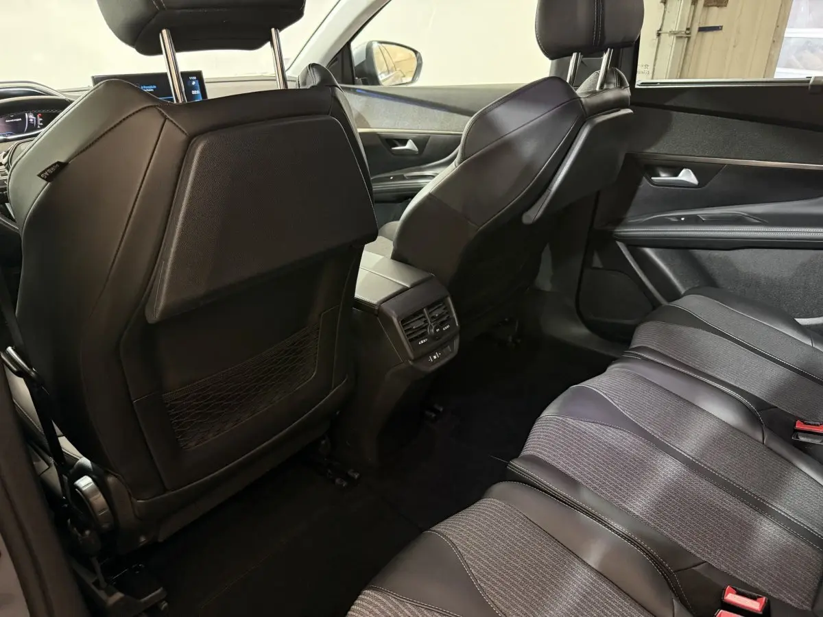Vue intérieure arrière droite du Peugeot 5008 2021, sièges en cuir noir et console centrale avec aérateurs.