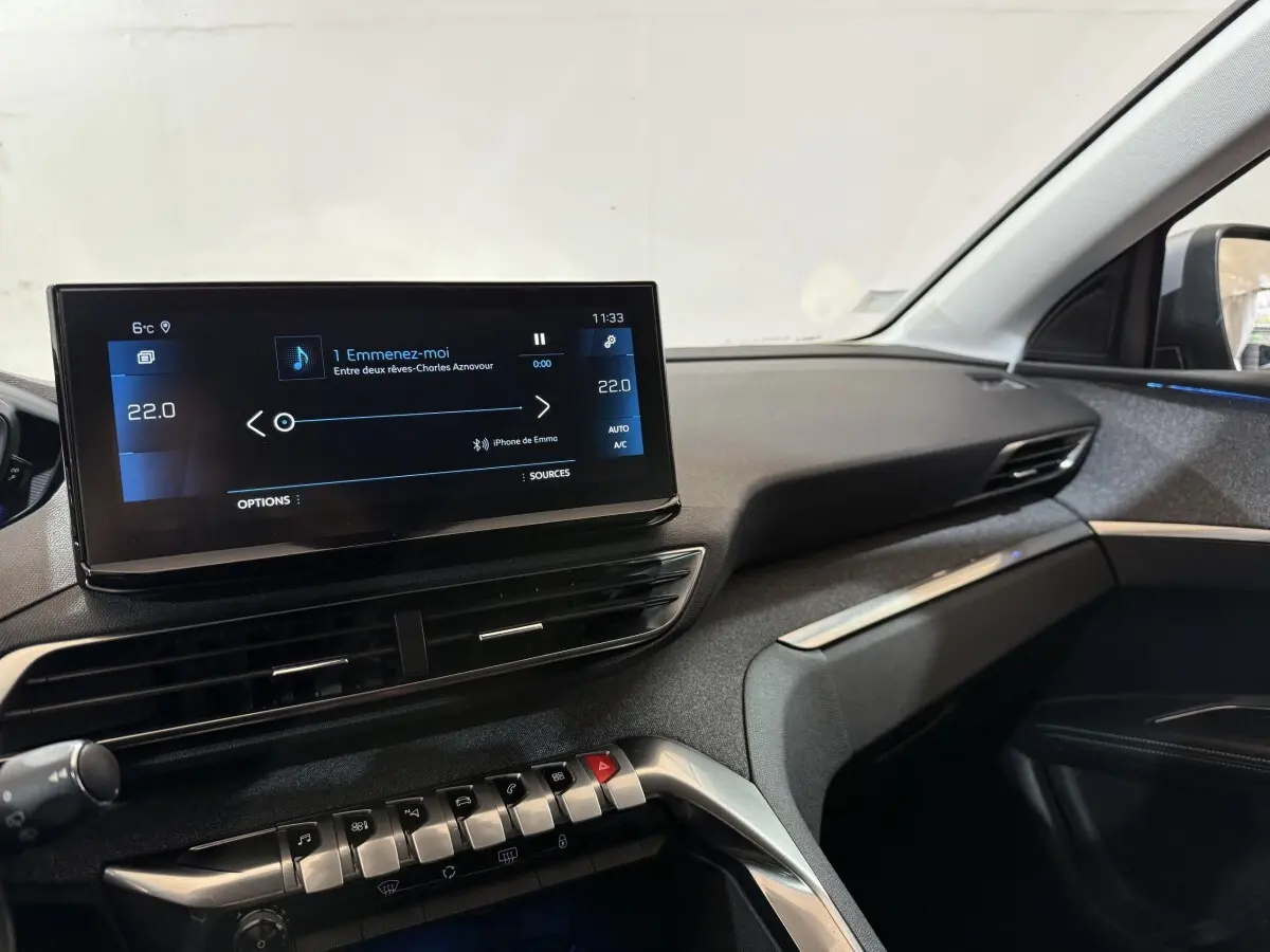 Vue intérieure côté passager du tableau de bord du Peugeot 5008 gris clair avec écran tactile central allumé.