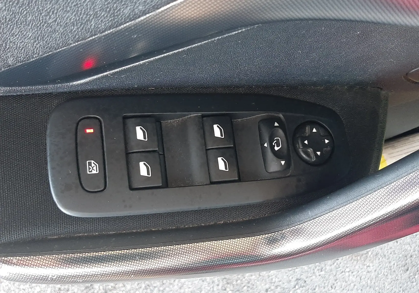 Gros plan sur les commandes électriques des vitres côté gauche d'une Peugeot 2008 rouge de 2016, version Allure.
