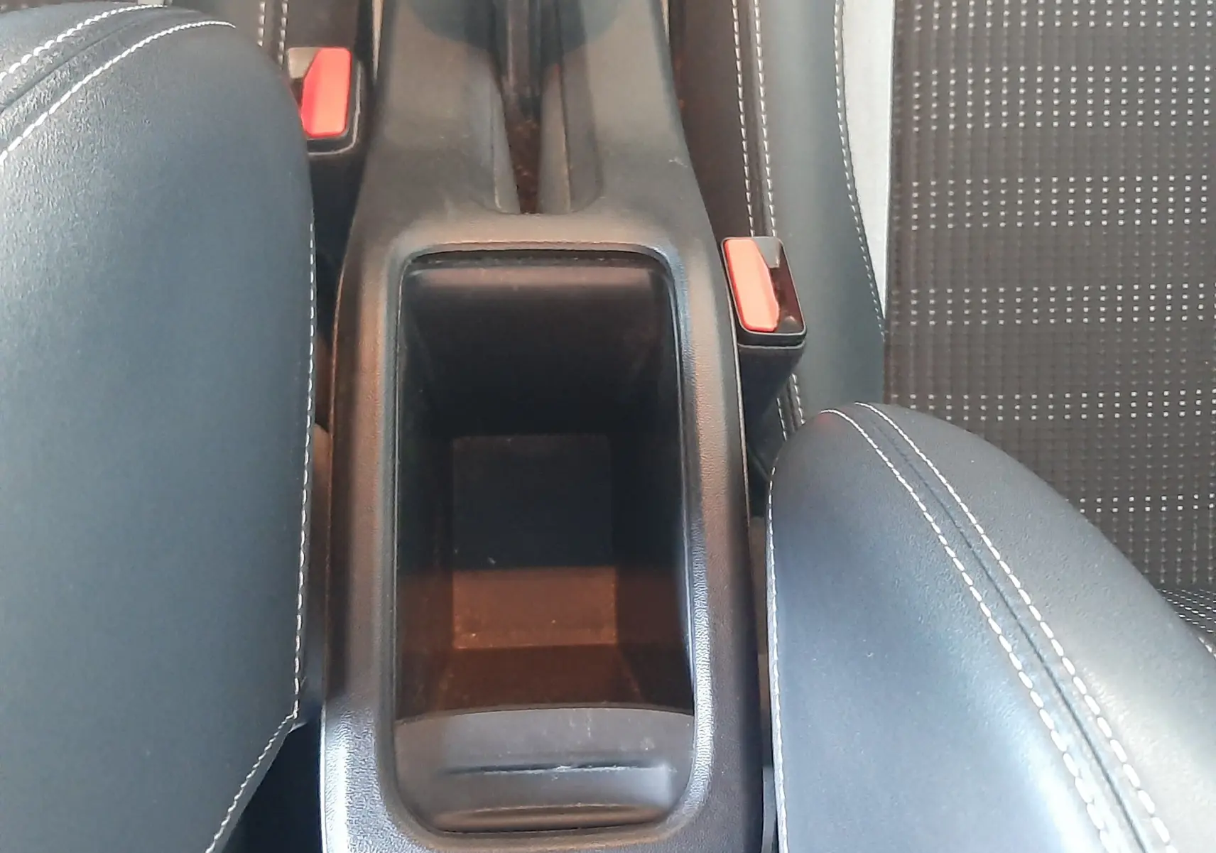 Vue plongeante sur la console centrale noire et les sièges tissu noir avec surpiqûres blanches du Peugeot 2008 rouge 2016