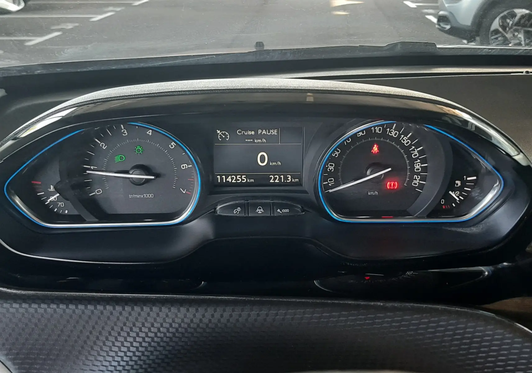 Vue rapprochée du tableau de bord digital d'une Peugeot 2008 rouge, affichant 114255 km et vitesse à 0 km/h.