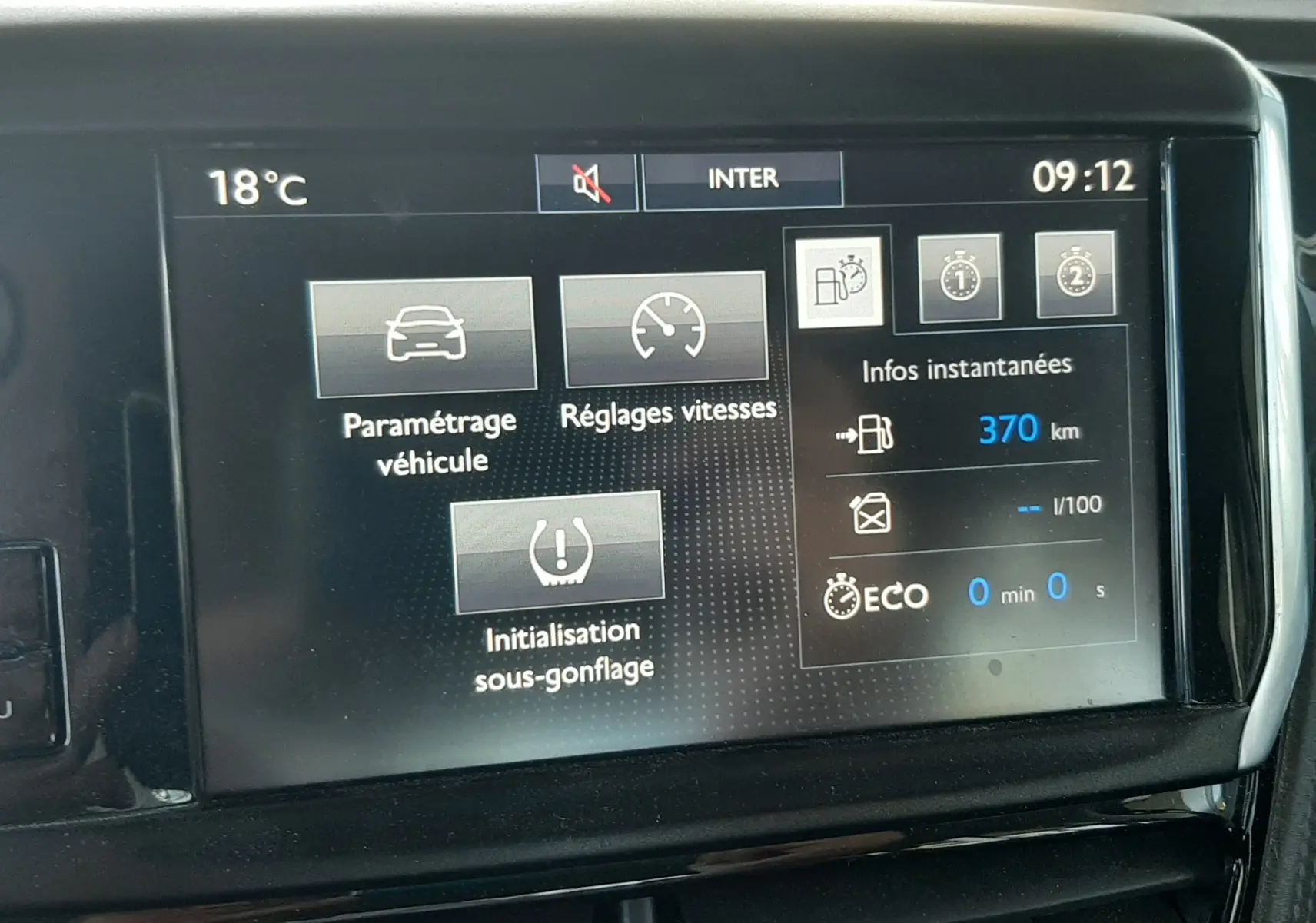 Écran tactile central du tableau de bord du Peugeot 2008 rouge de 2016 affichant les réglages du véhicule et l'autonomie restante.