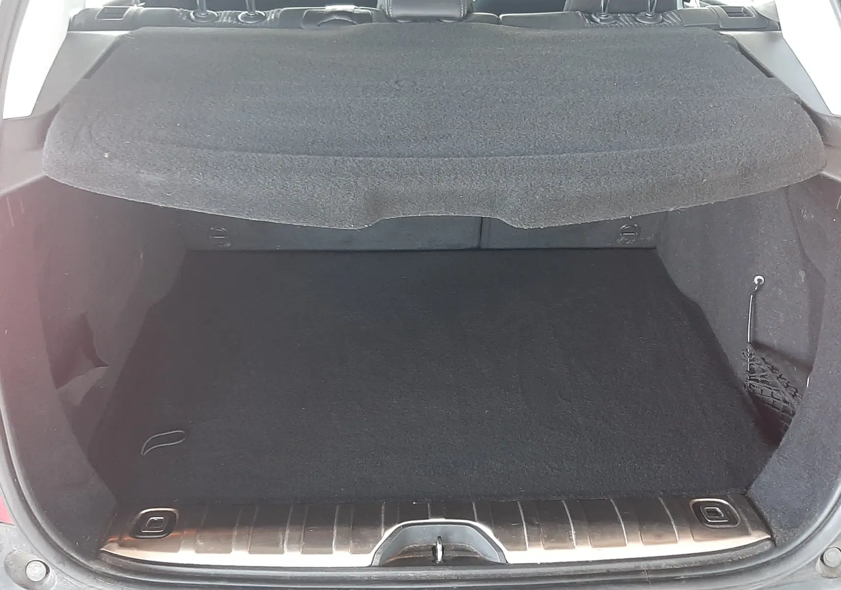 Coffre ouvert d'un Peugeot 2008 rouge, vue arrière montrant l'espace de chargement et l'intérieur noir du véhicule.