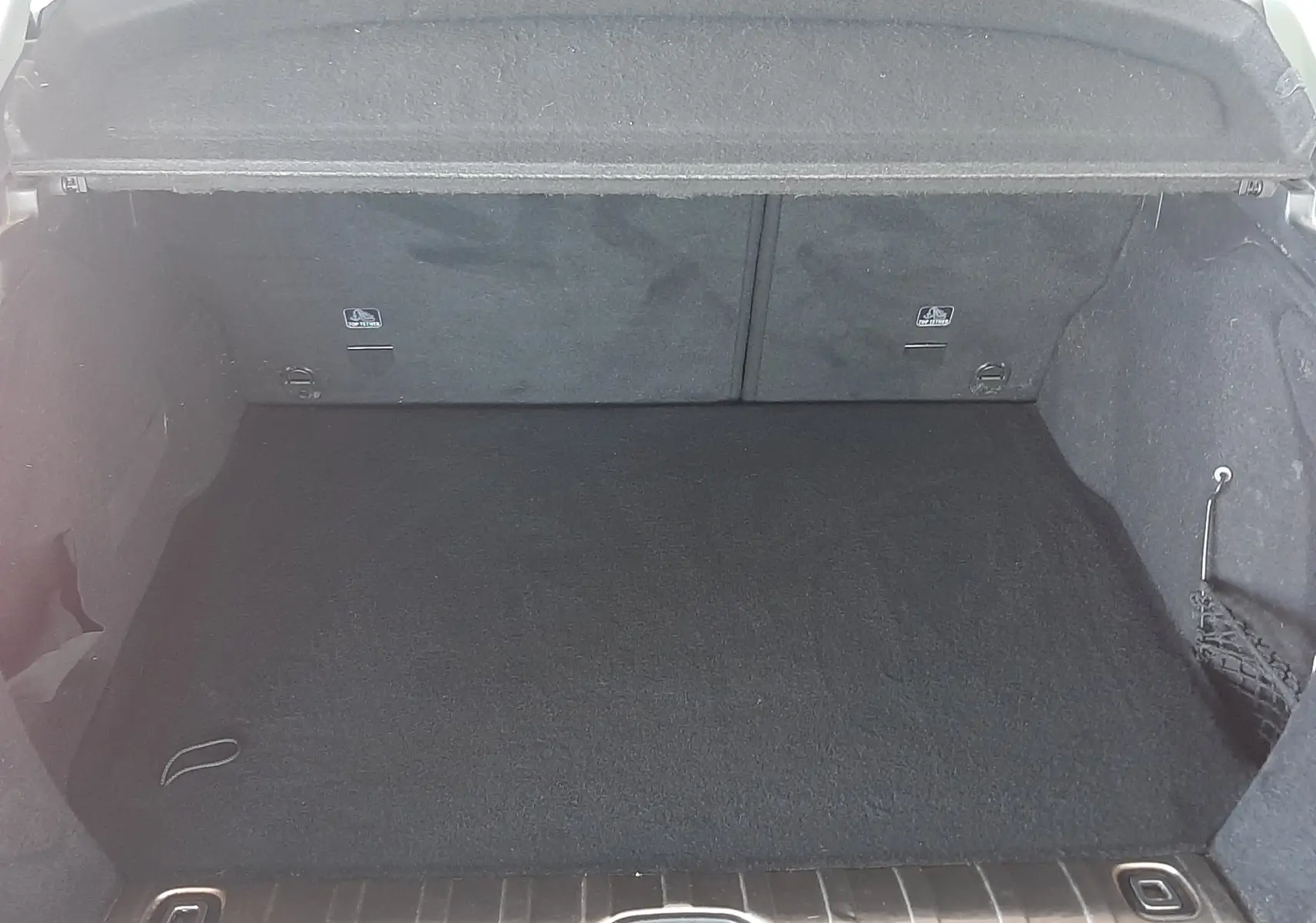 Vue intérieure du coffre noir du Peugeot 2008 rouge 2016, avec tablette arrière et partie avant du véhicule visible.