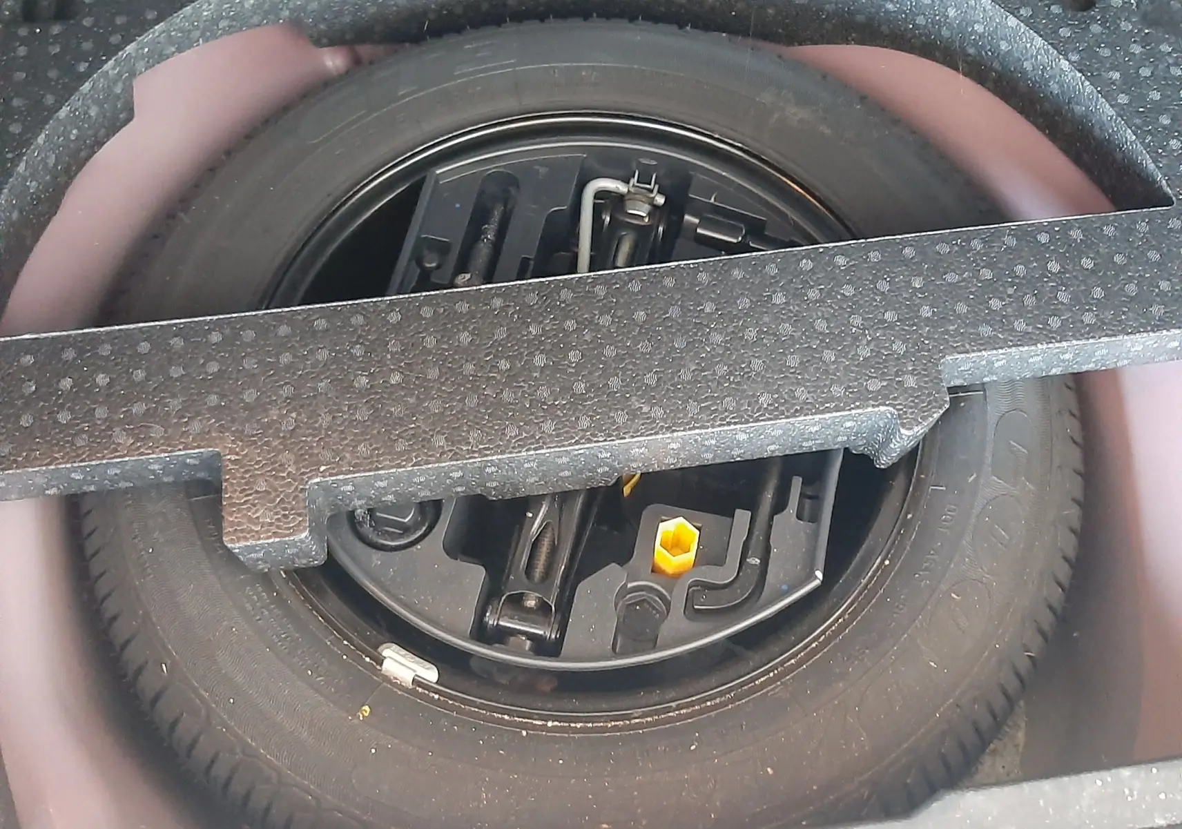 Roue de secours et outils de bord dans le coffre d'une Peugeot 2008 rouge 2016, version essence 1.2 PureTech.