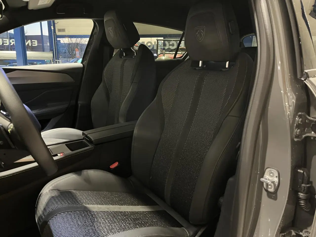 Sièges avant noirs en tissu et cuir avec logo Peugeot, vue intérieure côté gauche d'une 308 GT gris selenium 2024.